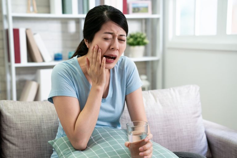 Person holding their jaw in discomfort