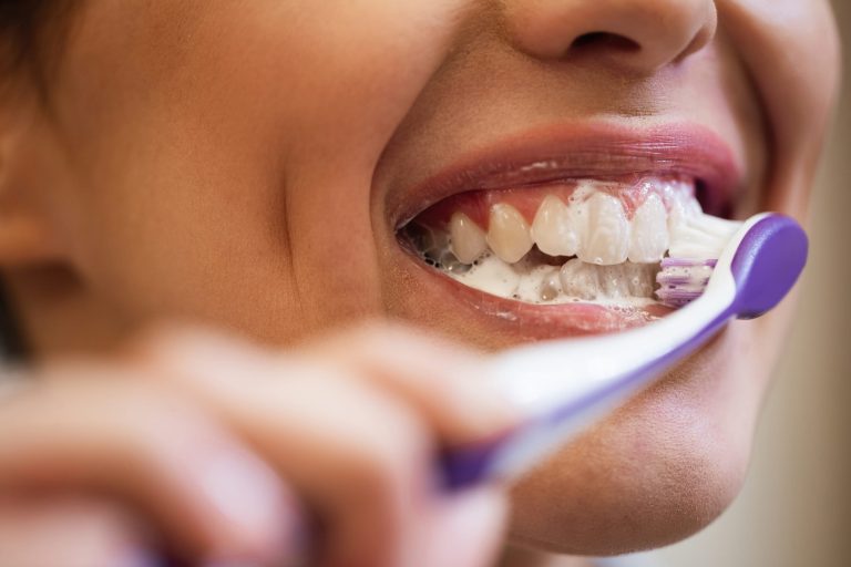 Woman brushing her teeth with a toothbrush to maintain oral hygiene